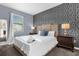 Serene bedroom with a patterned accent wall, a plush bed, and modern lamps at 2927 Fable St, Kissimmee, FL 34746