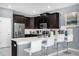 Modern kitchen with stainless steel appliances, dark wood cabinets, breakfast bar, and stylish white counter stools at 2927 Fable St, Kissimmee, FL 34746
