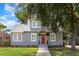 Charming gray home featuring a red door, manicured lawn, and mature trees enhancing curb appeal at 338 E Anderson St, Orlando, FL 32801