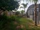 Tropical backyard featuring lush greenery, a privacy fence, and a screened enclosure at 340 Haversham Way, Davenport, FL 33897