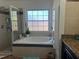 Bright bathroom showcasing a garden tub with a window, separate shower, and tiled surround at 340 Haversham Way, Davenport, FL 33897