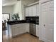 Modern kitchen features white cabinets, black countertops, stainless steel appliances, and tiled floors at 340 Haversham Way, Davenport, FL 33897