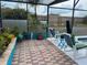 An enclosed, screened-in patio featuring a brick floor, tropical plants and comfortable seating near the pool at 340 Haversham Way, Davenport, FL 33897