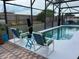 Screened-in pool area with stylish seating and a clear blue pool surrounded by lush landscaping at 340 Haversham Way, Davenport, FL 33897