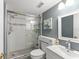 Cozy bathroom featuring tiled shower with glass door, white fixtures, and textured wallpaper at 3475 Flossmoor Ave # 103, Orlando, FL 32822
