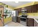 Kitchen features stainless appliances, brown cabinets, ample counter space, and natural light at 3475 Flossmoor Ave # 103, Orlando, FL 32822