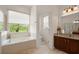 Bright bathroom featuring a soaking tub, vanity with granite countertop, and a separate toilet room at 3696 Peacepipe Ct, Clermont, FL 34711