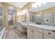 Elegant bathroom featuring dual vanities, frameless glass shower, and archway to an adjacent room at 3844 Bowfin Trl, Kissimmee, FL 34746