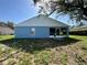 Rear view of the home featuring a screen enclosed porch and blue siding near a grassy backyard at 703 Tartan Loop, Lake Wales, FL 33853