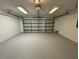 Clean, empty garage with painted walls, a garage door, a concrete floor and overhead lighting at 703 Tartan Loop, Lake Wales, FL 33853