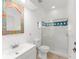 Bright bathroom featuring colorful mirror, white vanity, toilet, and glass-enclosed shower with blue tile accent at 7699 Milano Dr, Orlando, FL 32835