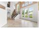 Sunlit living room with soaring ceilings, arched windows, staircase, and neutral tile flooring at 7699 Milano Dr, Orlando, FL 32835