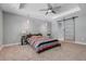 Spacious bedroom boasts a tray ceiling, ceiling fan, carpet flooring, and a sliding barn door to ensuite bathroom at 812 Deep Wood Ct, Fruitland Park, FL 34731
