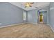 Carpeted bedroom with blue walls, ceiling fan, and doorway to ensuite bathroom at 887 Lancer Cir, Ocoee, FL 34761