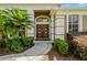 Elegant front entrance with a beautiful wood door, lush landscaping, and a paved walkway at 887 Lancer Cir, Ocoee, FL 34761