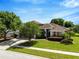 Charming home with lush green lawn, mature landscaping, and a driveway leading to a garage at 887 Lancer Cir, Ocoee, FL 34761