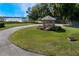 Scenic view of a charming gazebo nestled in a grassy common area, complemented by mature landscaping and lake access at 887 Lancer Cir, Ocoee, FL 34761