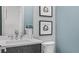 Contemporary powder room with elegant wood vanity, stylish mirror, and unique circular artwork at 960 Club Cresswind Dr, Lady Lake, FL 32159