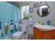 Well-lit bathroom with a surfboard shower curtain, window plants, and a wood vanity at 11435 Aries Dr, Orlando, FL 32837