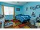 Blue bedroom with a large window, playful artwork, and an area rug, creating a lively space at 11435 Aries Dr, Orlando, FL 32837