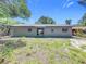 Back exterior view showing simple landscaping, a sliding glass door entrance, and a light color scheme at 1307 Jean Ct, Eustis, FL 32726