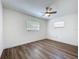 Bright bedroom featuring modern ceiling fan, wood-look floors, and natural light from two windows at 1307 Jean Ct, Eustis, FL 32726