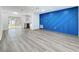 Open-concept living room flowing into the kitchen area, with gray floors and a bold blue accent wall at 1307 Jean Ct, Eustis, FL 32726