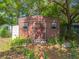 View of a brown wooden storage shed with a door, plants, and pavers at 1307 Jean Ct, Eustis, FL 32726