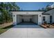 Open two car garage with modern doors, leading to a well maintained front lawn and yard at 13419 Sw 77Th Ave, Ocala, FL 34473