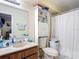 Bathroom with a vanity sink, toilet, shower with curtain, and shelving, creating a functional and practical space at 1748 Foxhall Cir # 1748, Kissimmee, FL 34741