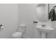 This powder room features a modern floating sink, toilet, and circular mirror at 2223 Blue Salvia St, Clermont, FL 34711