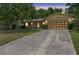 Dusk view of a single-story brick home with a long cracked driveway, brown shutters, and a mature tree at 244 Angeles Rd, Debary, FL 32713