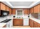 Efficient kitchen with wood cabinets, white appliances, and a bright window over the sink at 244 Angeles Rd, Debary, FL 32713