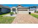 Charming home features a two-car garage, brick driveway, manicured landscaping, and a well-maintained lawn at 2456 Varenna Loop, Kissimmee, FL 34741