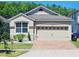 Charming home features a two-car garage, brick driveway, manicured landscaping, and a well-maintained lawn at 2456 Varenna Loop, Kissimmee, FL 34741