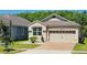 Charming home features a two-car garage, brick driveway, manicured landscaping, and a well-maintained lawn at 2456 Varenna Loop, Kissimmee, FL 34741