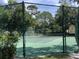 Fenced tennis court surrounded by lush greenery and trees for added privacy during matches at 334 N Shadowbay Blvd, Longwood, FL 32779