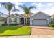 Inviting single-story home with a well-manicured lawn, brick driveway, and lush palm trees under a clear blue sky at 3925 Green Sabal Dr, Orlando, FL 32824