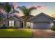 Charming single-story home with a two-car garage, beautiful landscaping, and tropical palm trees against a colorful sunset backdrop at 3925 Green Sabal Dr, Orlando, FL 32824