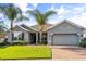 Attractive one-story home with green lawn, a brick driveway, gray exterior and decorative palm trees at 3925 Green Sabal Dr, Orlando, FL 32824
