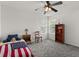 Cozy bedroom with gray carpet, a ceiling fan, a bed with American flag blanket, and a bookcase near bright windows at 4249 Andover Cay Blvd, Orlando, FL 32825