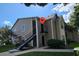 Two-story condo with tan siding, black stairs, second story balcony, and landscaping at 4704 Walden Cir # 21, Orlando, FL 32811