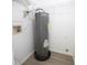 A gray Rheem water heater sits on a black pan, surrounded by wire shelving in a utility closet at 4704 Walden Cir # 21, Orlando, FL 32811