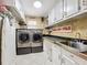 Well-organized laundry room with white cabinets, countertops, sink, and modern washer and dryer at 5127 Leeward Way, Orlando, FL 32809
