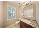 Half bath featuring a granite countertop, decorative mirror, and plantation shutters at 5262 Baskin St, Orlando, FL 32814