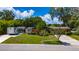 Landscaped front yard of a brick home featuring a screened lanai, RV parking, and carport at 7 Westchester Dr, Kissimmee, FL 34744
