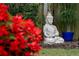 Close-up of a serene Buddha statue nestled among lush greenery and vibrant red flowers at 7 Westchester Dr, Kissimmee, FL 34744