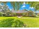 Charming brick home featuring manicured lawn, mature trees, and a welcoming red front door at 8812 S Bay Dr, Orlando, FL 32819