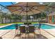 Enjoy outdoor dining by the pool with a glass table, four chairs, and an umbrella at 8812 S Bay Dr, Orlando, FL 32819