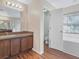 Well-lit bathroom featuring double vanity sinks, tile tub surround and a separate toilet area at 10247 Mason Loop, Clermont, FL 34711